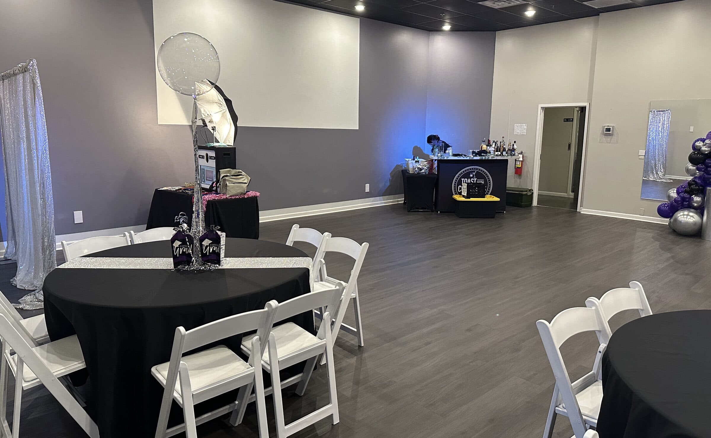 Graduation setup with black round tables, silver sequin runners, Congrats Grad centerpieces, a silver sequin drape and a bar station along the back wall at The Cove at St. Johns, Fruit Cove FL