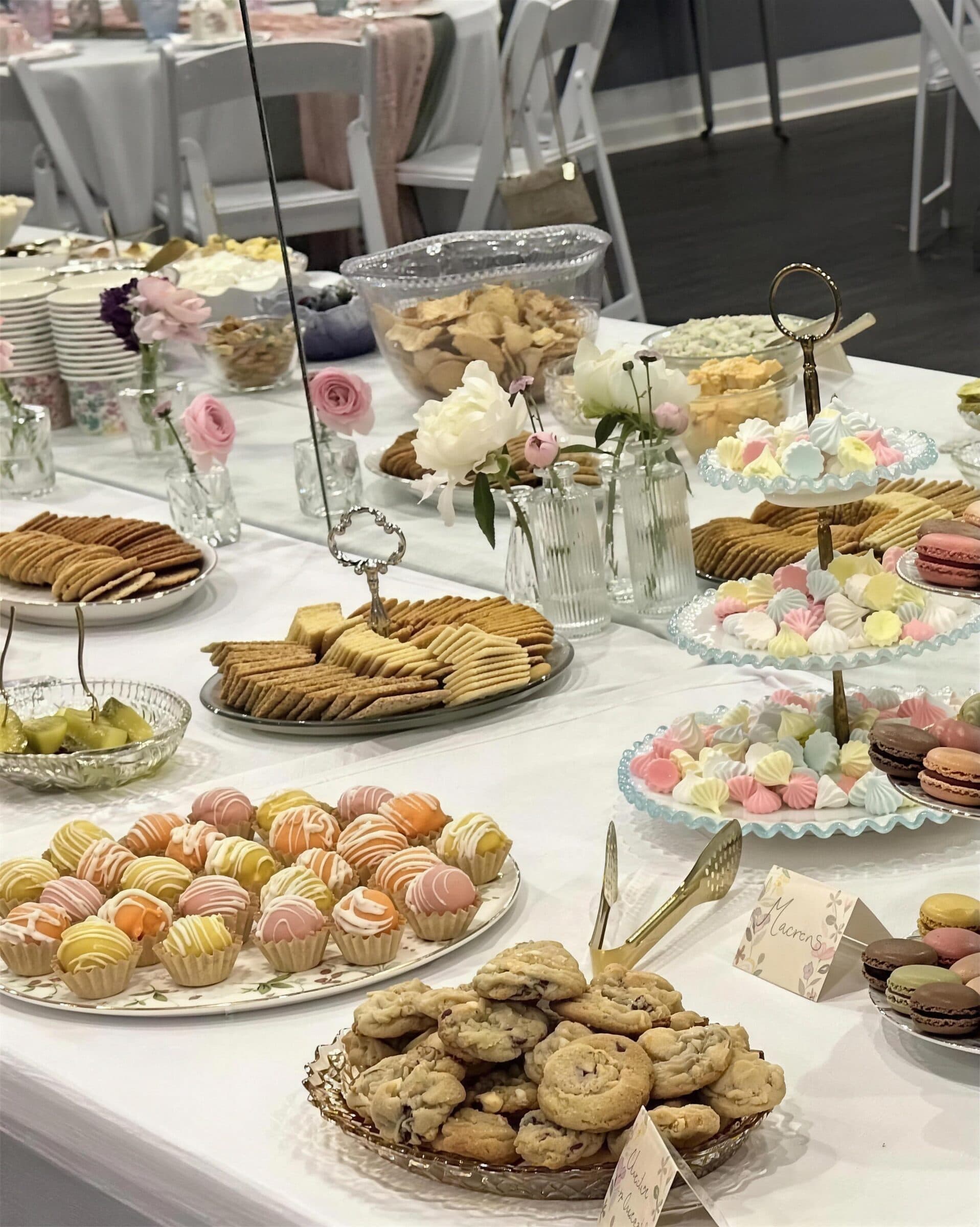 Dessert table with tiered stands of pastel meringues and macarons, cake bites, cookies, crackers and bud vases of pink and white roses at The Cove at St. Johns, Fruit Cove, St. Johns County FL