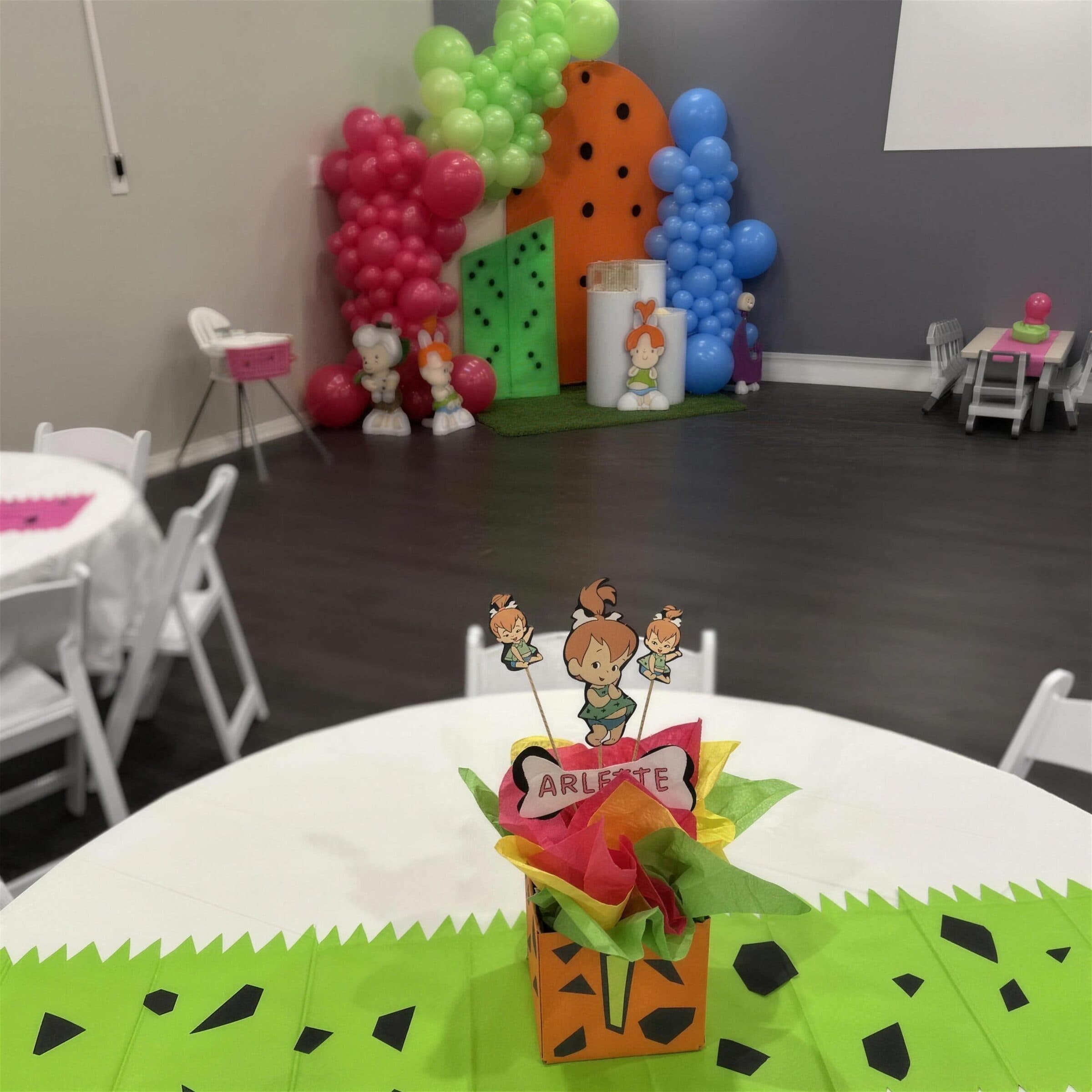 Stone-age first birthday room with green paper table skirts, a tissue-paper centerpiece and kids' tables at The Cove at St. Johns, Fruit Cove, St. Johns County FL