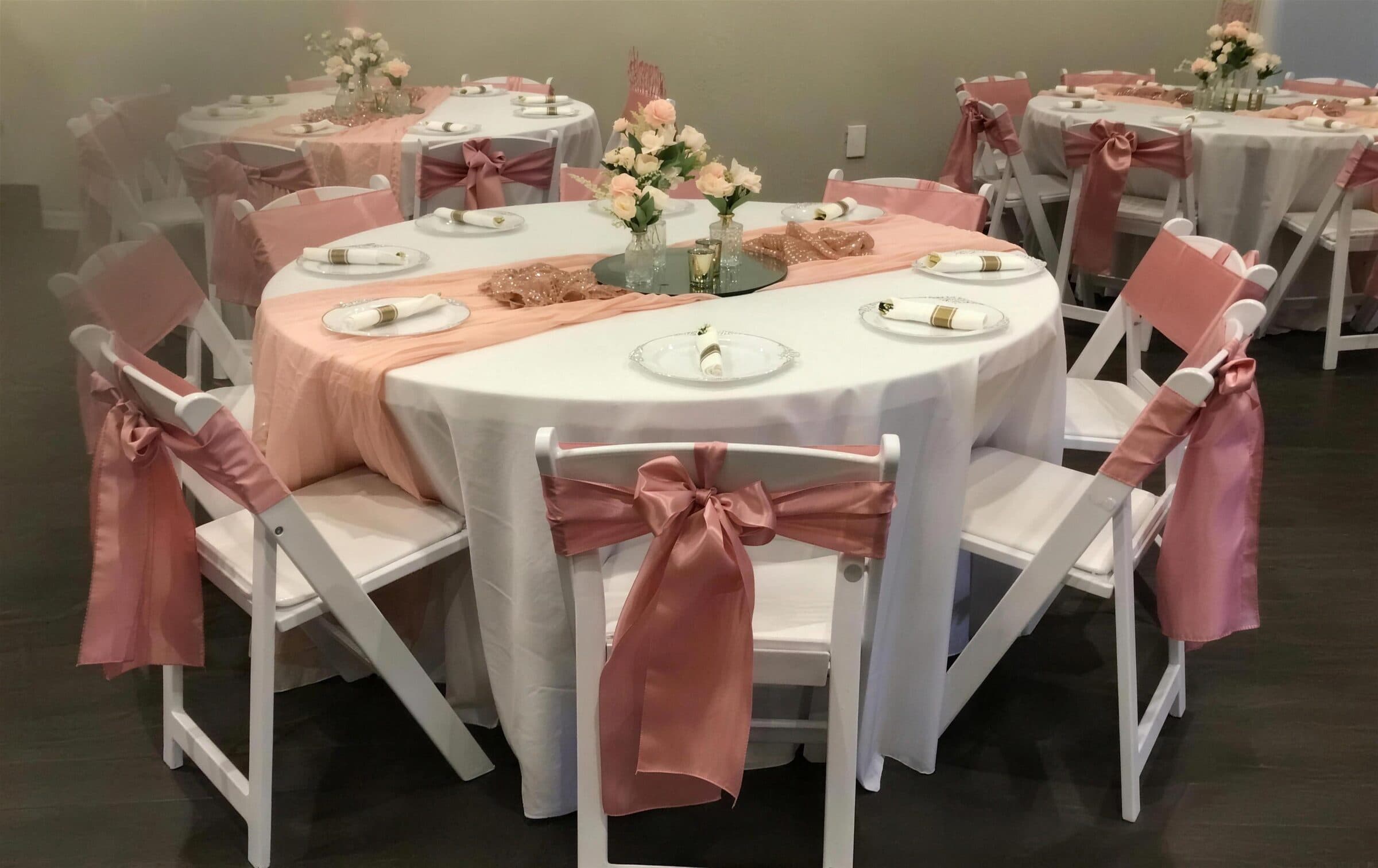 Blush and rose gold rounds with peach chiffon runners, silver-rimmed plates and small rose bouquets at a birthday party at The Cove at St. Johns, Fruit Cove, St. Johns County FL