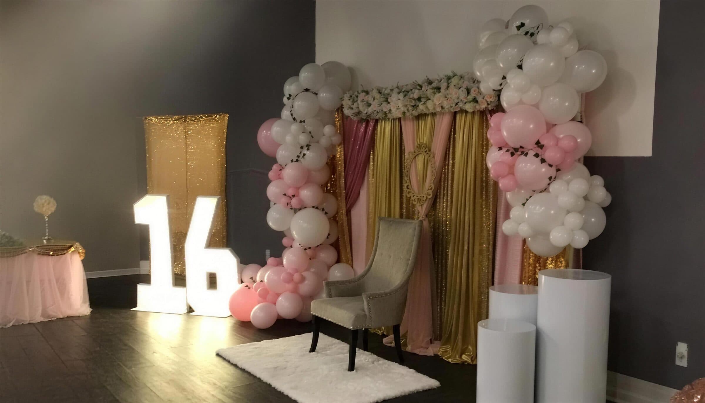 Lit marquee 16 beside a pink and white balloon arch, gold sequin draping and a throne chair at a Sweet 16 at The Cove at St. Johns, Fruit Cove FL