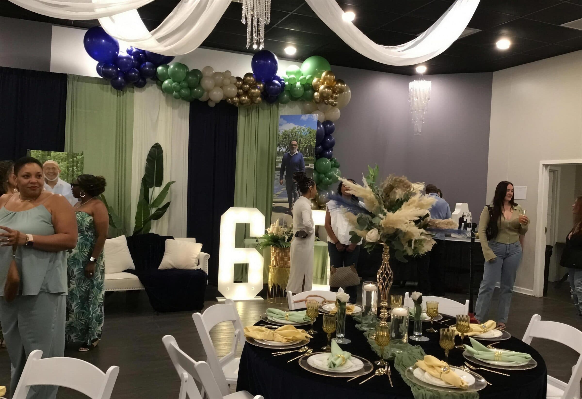 White ceiling draping and a crystal chandelier over navy tables with sage runners and a tall pampas centerpiece at The Cove at St. Johns, St. Johns County FL