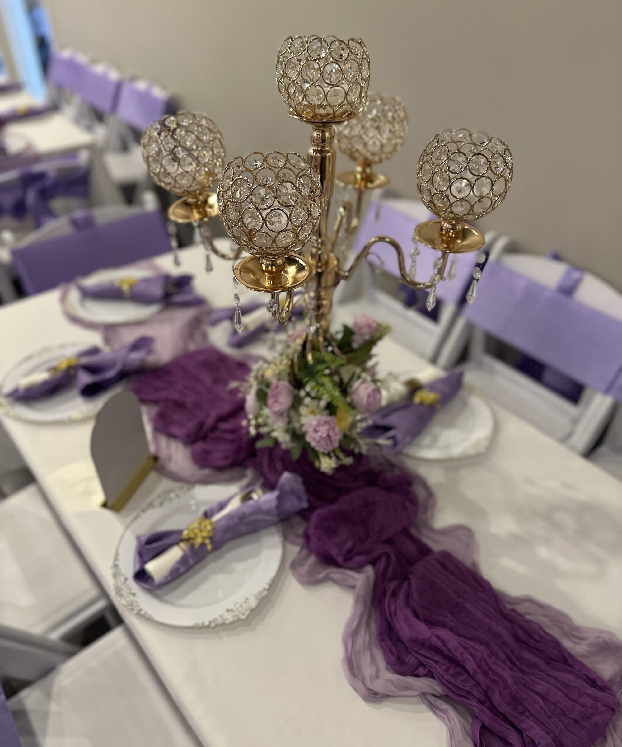 Gold crystal candelabra centerpiece with a plum cheesecloth runner, lavender napkins and beaded chargers at a quinceanera at The Cove at St. Johns, near Jacksonville, FL