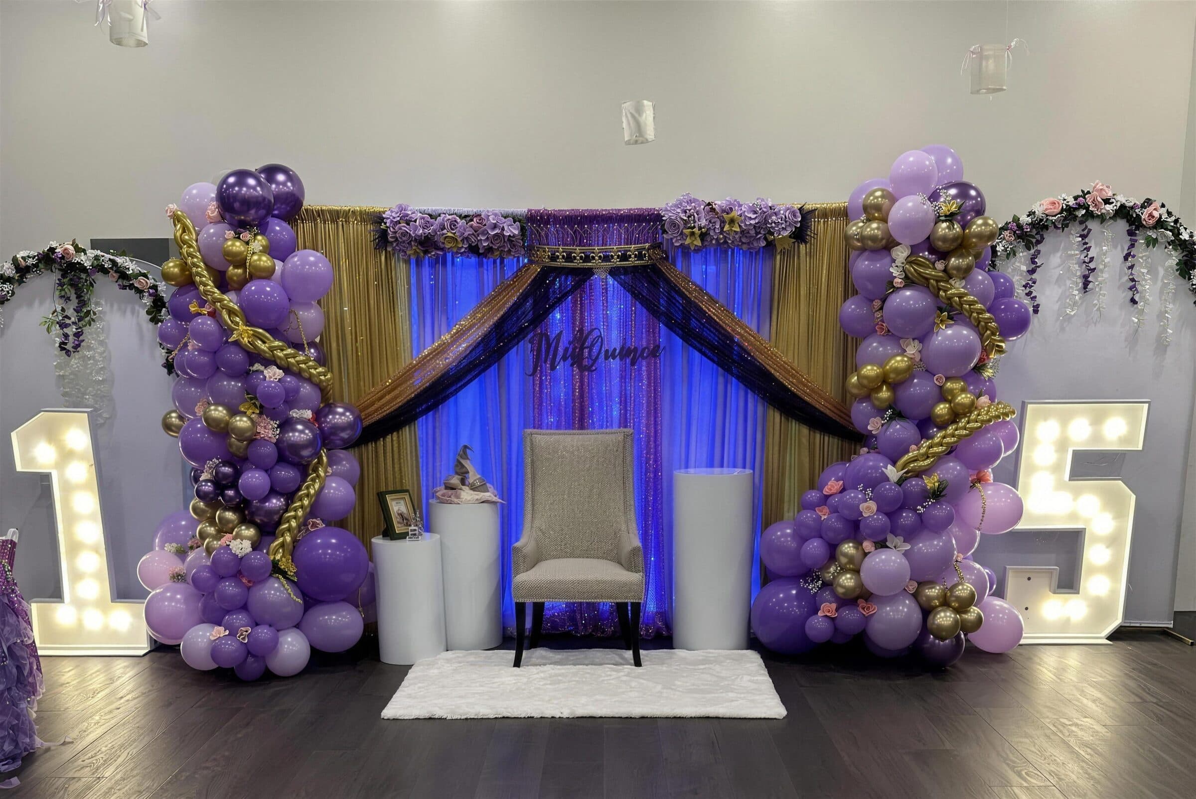 Purple and gold quinceanera backdrop with balloon columns, sequin draping, a throne chair and lit marquee 1 and 5 numbers at The Cove at St. Johns, Fruit Cove, St. Johns County FL