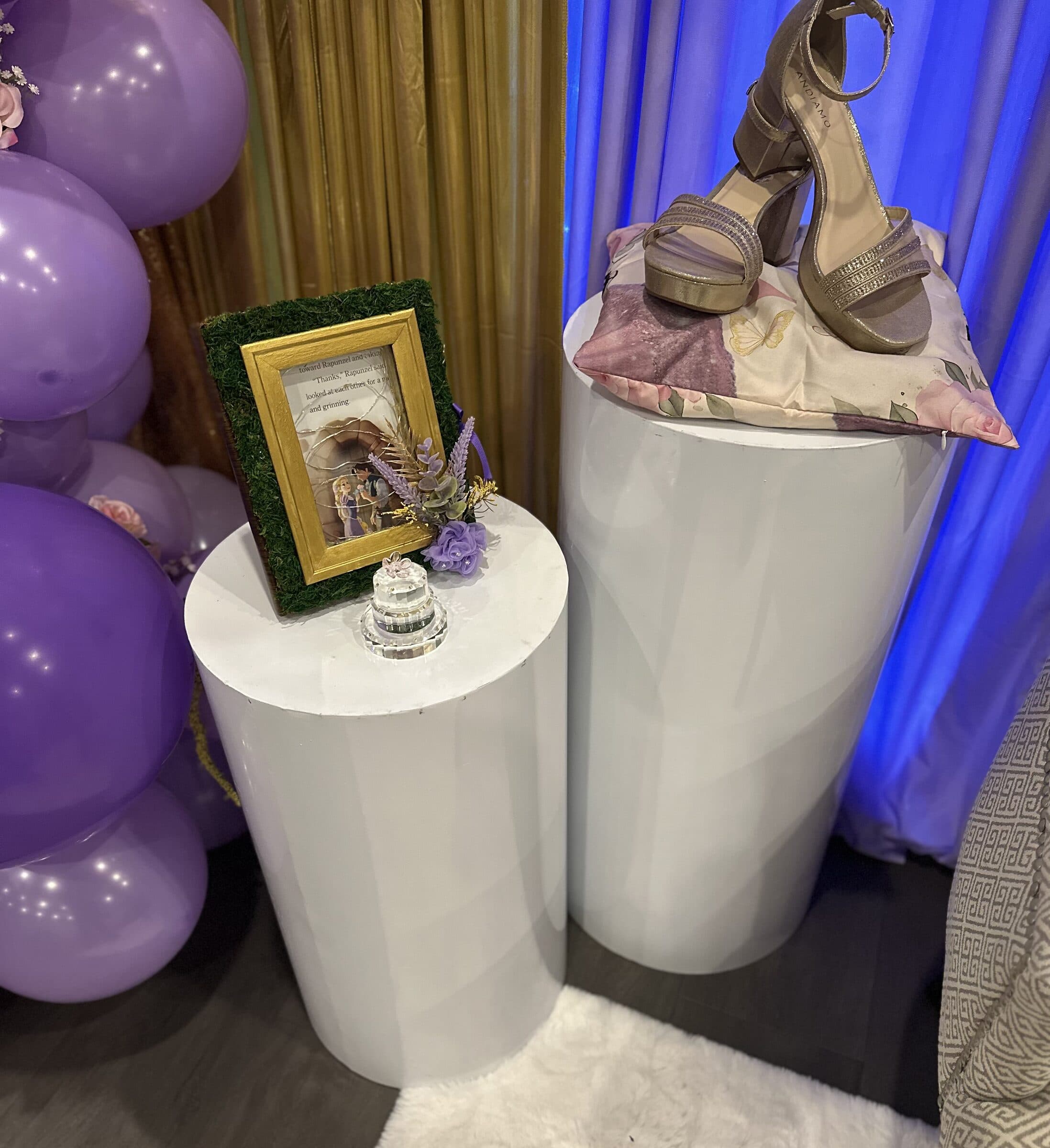 Keepsake pedestals at a quinceanera at The Cove at St. Johns, St. Johns County FL - a gold storybook frame, a crystal cake figurine and the ceremonial heels on a floral pillow