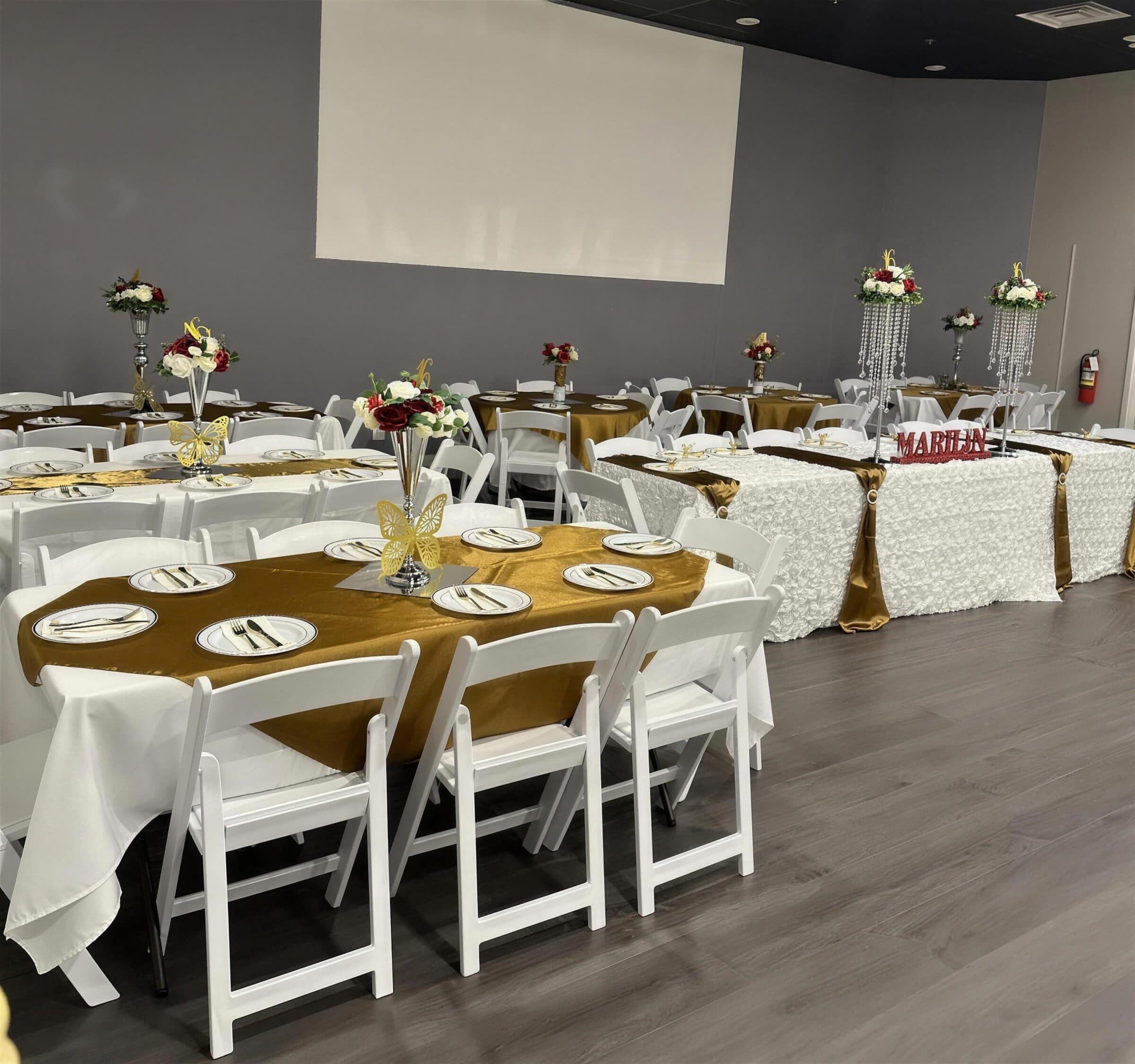 Sweet 16 banquet in white and gold - satin runners, red and white rose trumpet vases, butterfly cutouts and a rosette-skirted head table at The Cove at St. Johns, St. Johns County FL