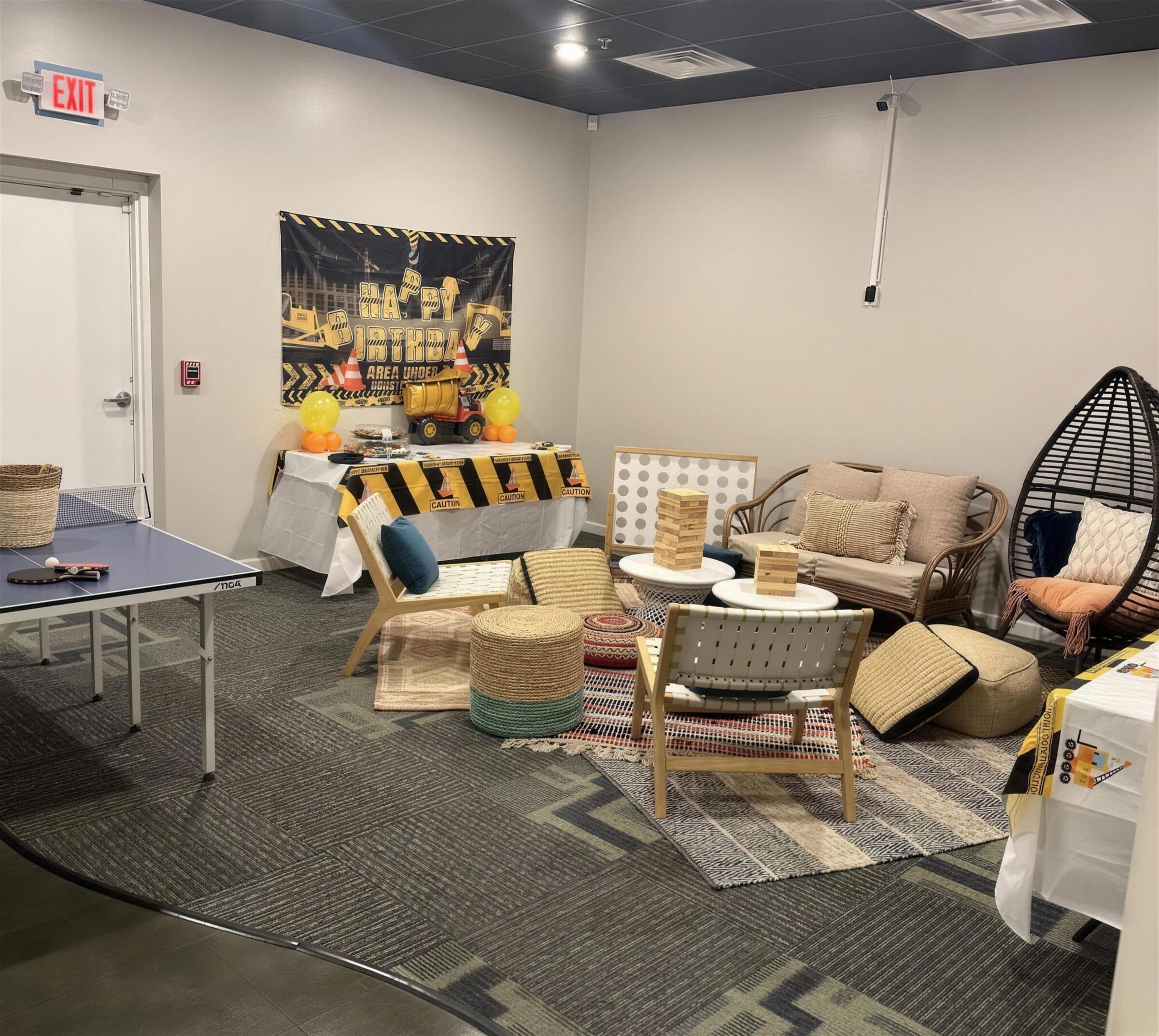 Construction-theme birthday in the lounge - caution-tape banner and table skirt, toy dump truck, ping-pong table, giant Jenga and rattan seating at The Cove at St. Johns, St. Johns County FL