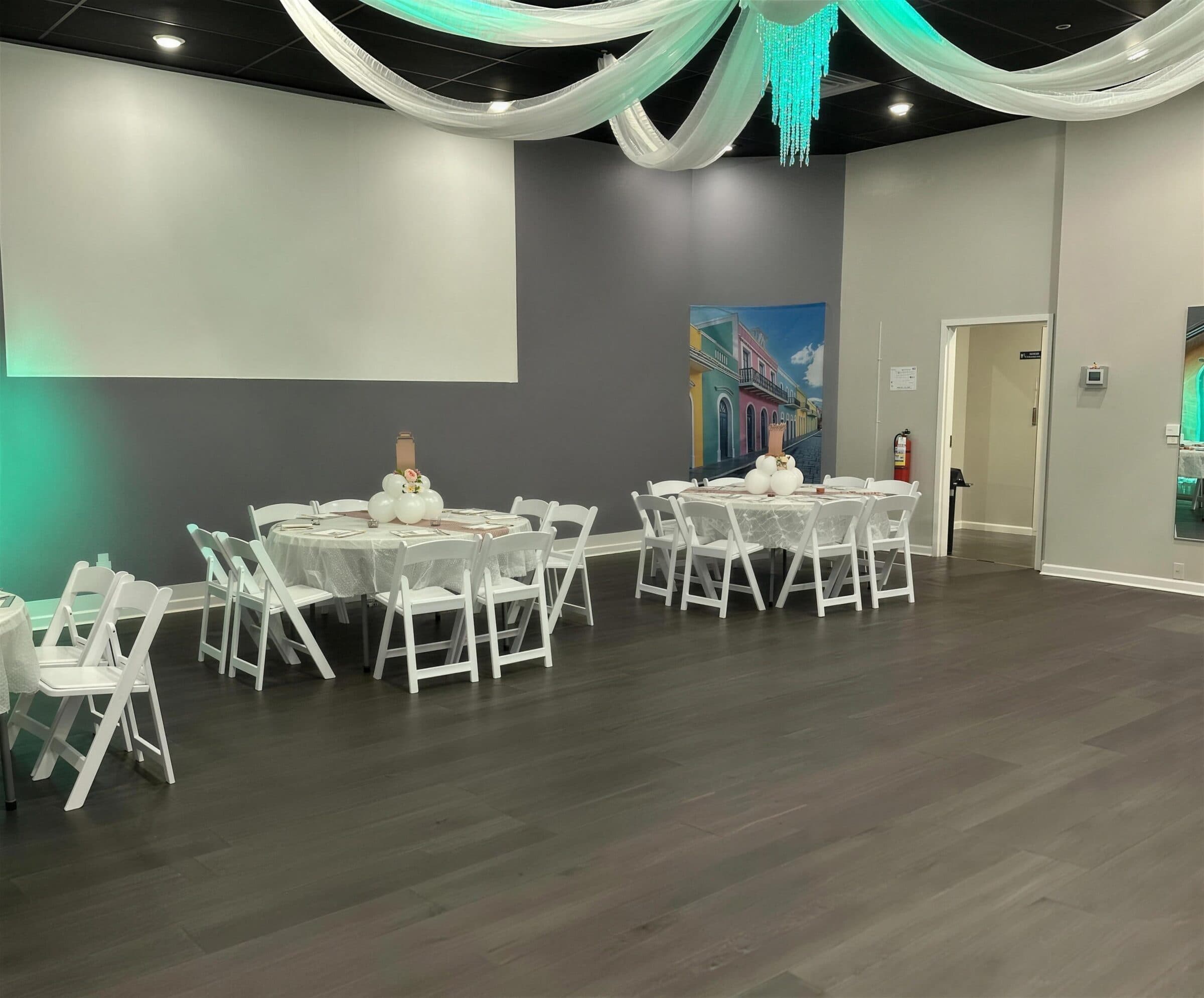 Round guest tables with white linens, blush runners and white balloon centerpieces under swagged ceiling draping and teal uplighting at The Cove at St. Johns, Fruit Cove FL