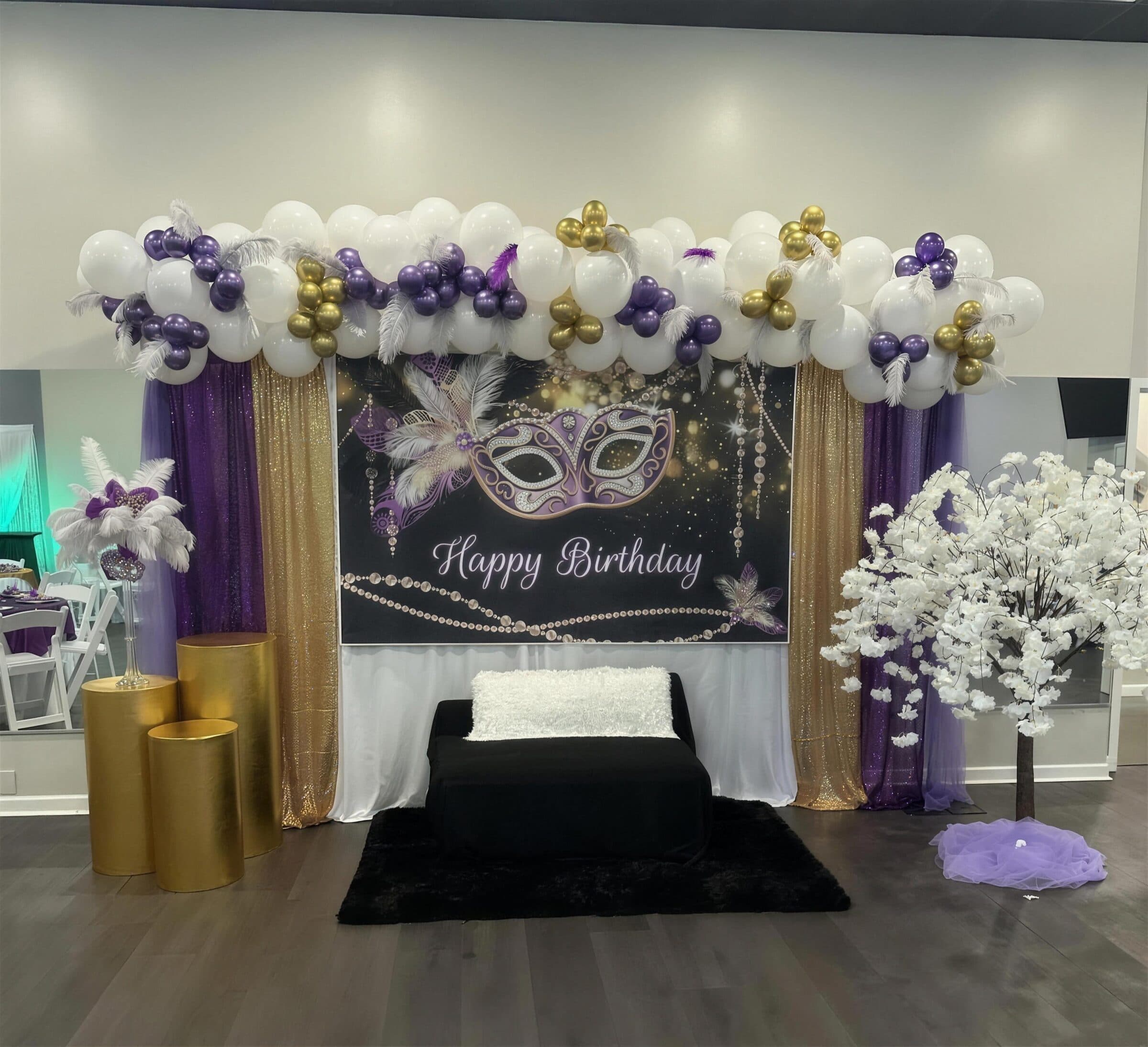 Masquerade Happy Birthday backdrop with purple, gold and white balloons, feathers, gold sequin drapes and a black chaise at The Cove at St. Johns, St. Johns County FL