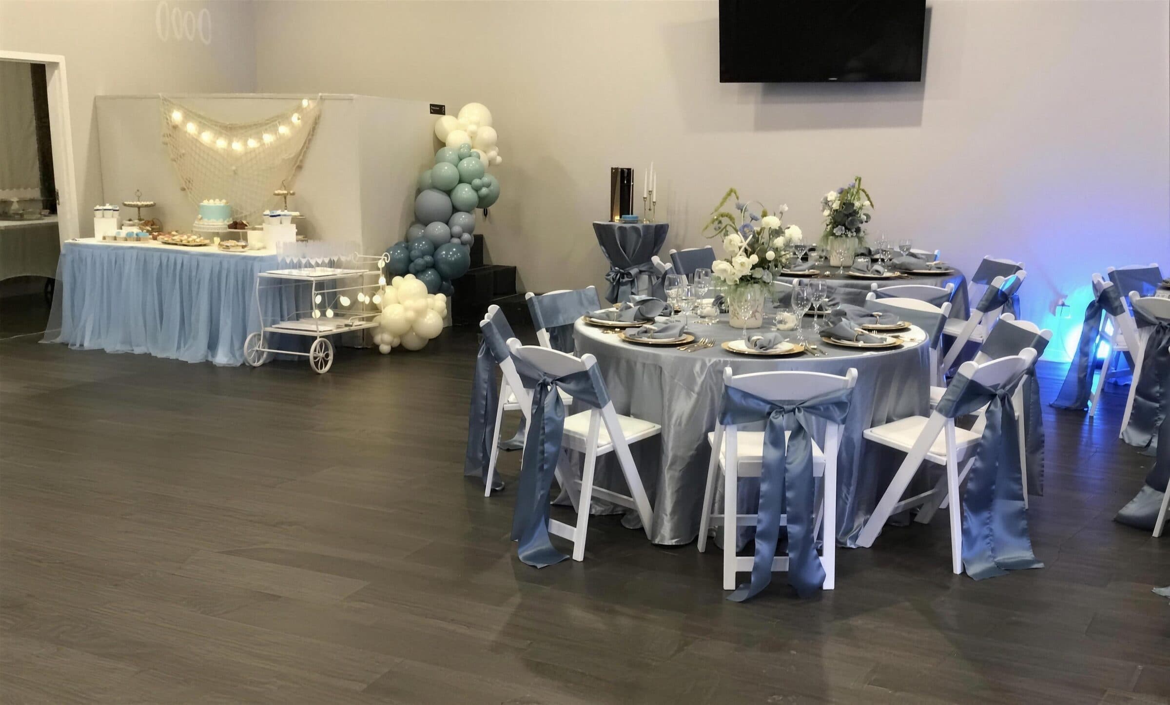 Dusty blue reception at The Cove at St. Johns, Fruit Cove, St. Johns County FL - satin chair sashes, gold chargers and a dessert table with fishing net and string lights