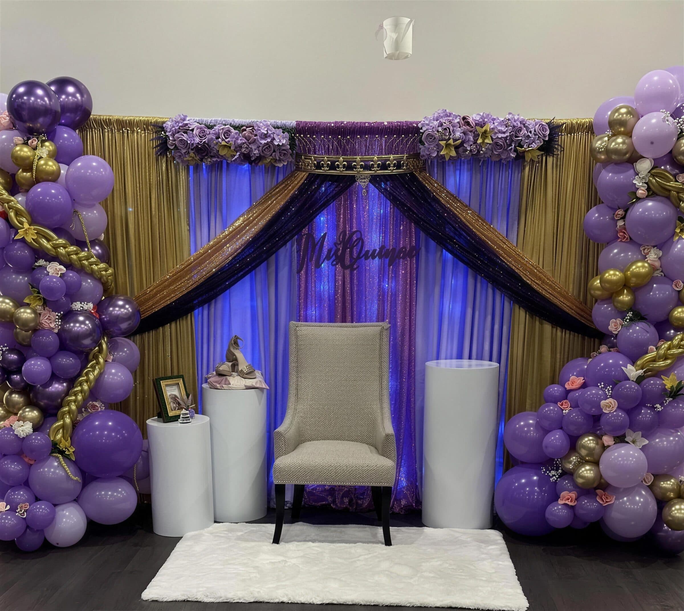 Mis Quince throne backdrop with gold and purple draping, lavender rose garlands, purple and gold balloon columns, pedestals and a high-back chair at The Cove at St. Johns, St. Johns County FL