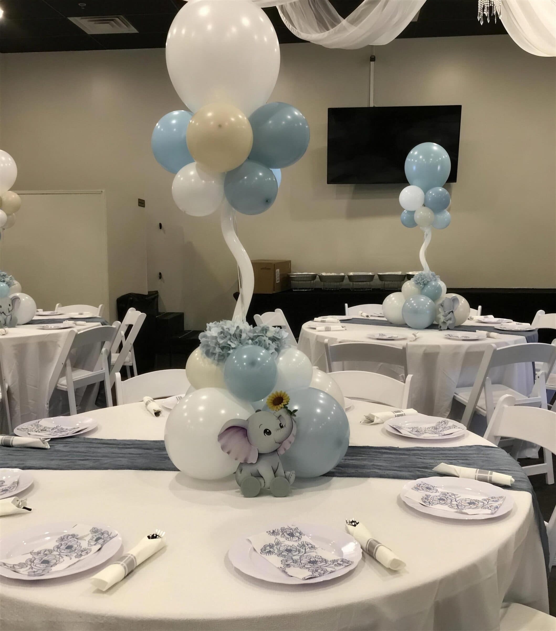 Close-up of a blue, cream and white balloon centerpiece with a gray elephant cutout and floral-print plates on a slate runner, baby shower at The Cove at St. Johns, Fruit Cove FL