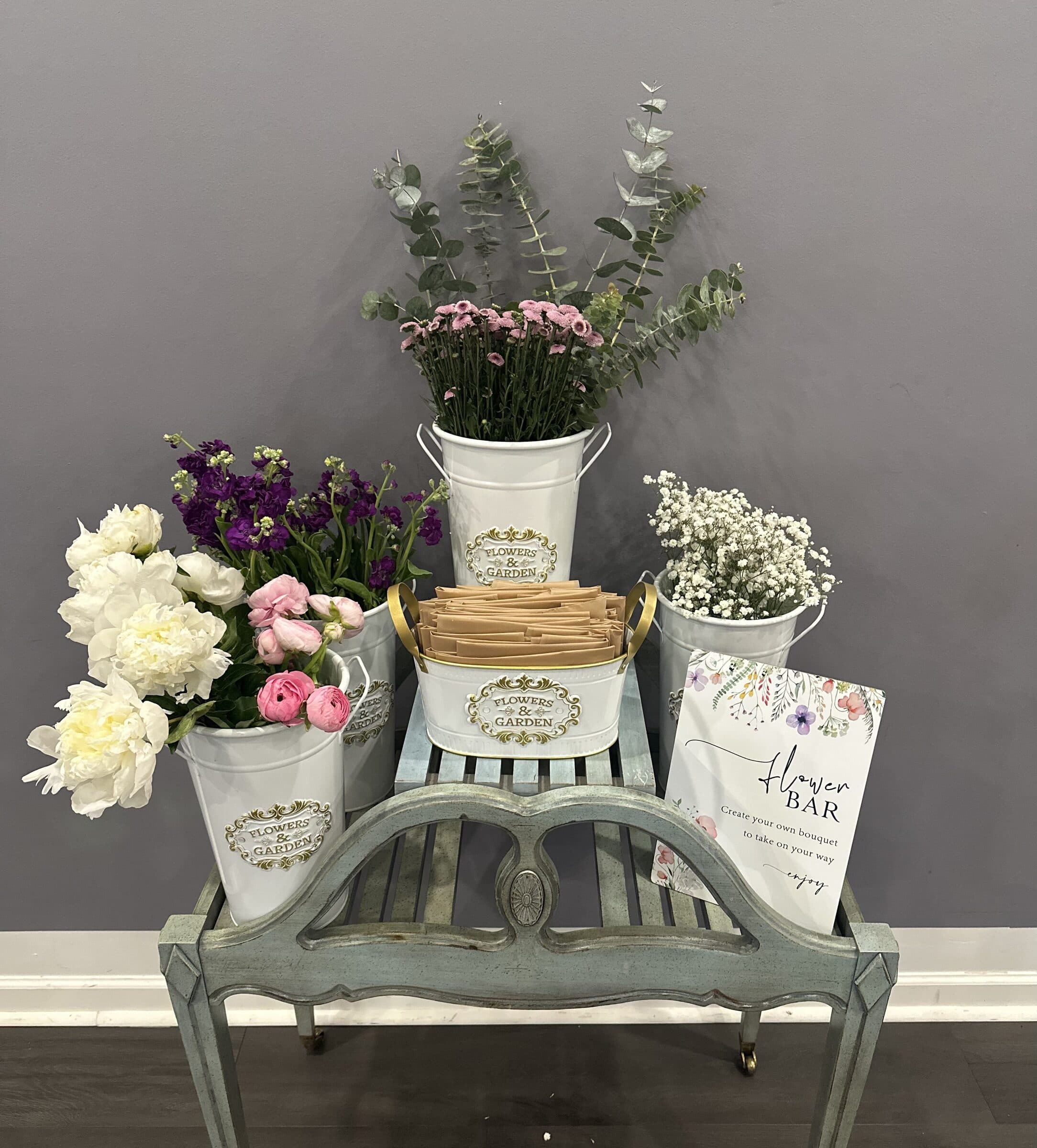 Flower bar on a bench: buckets of peonies, ranunculus, stock and baby's breath with kraft wraps and a lettered sign, bridal tea at The Cove at St. Johns, near Jacksonville, FL