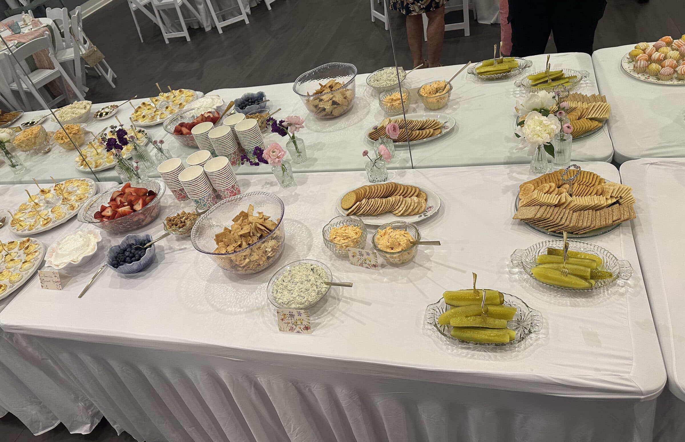 Appetizer table in white linen holding deviled eggs, strawberries, blueberries, cracker trays, dips and pickle spears at a bridal tea at The Cove at St. Johns, St. Johns County FL