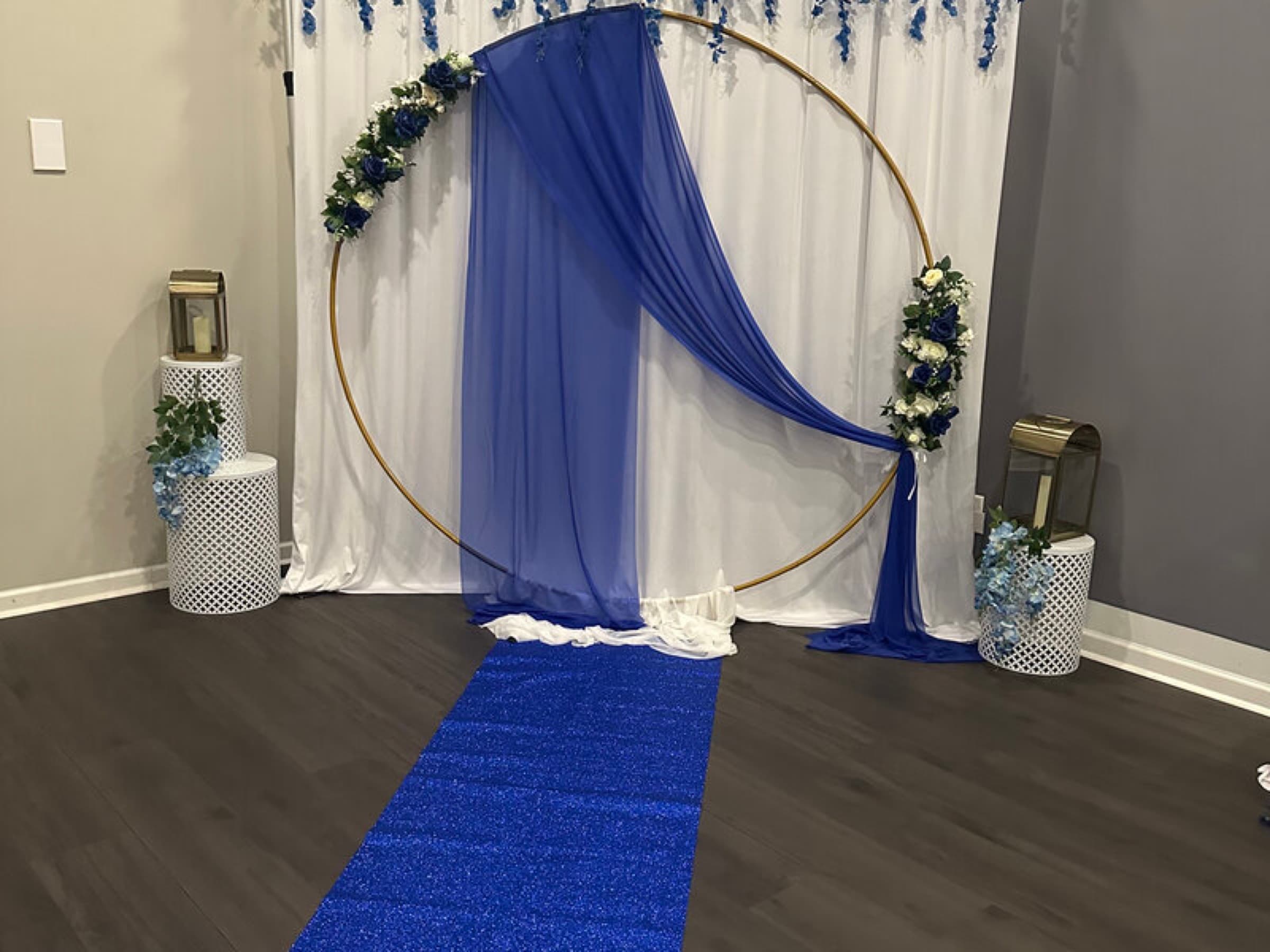 Royal blue and white wedding ceremony backdrop with gold circle arch, chiffon draping, and glitter aisle runner at The Cove at St. Johns, Fruit Cove FL