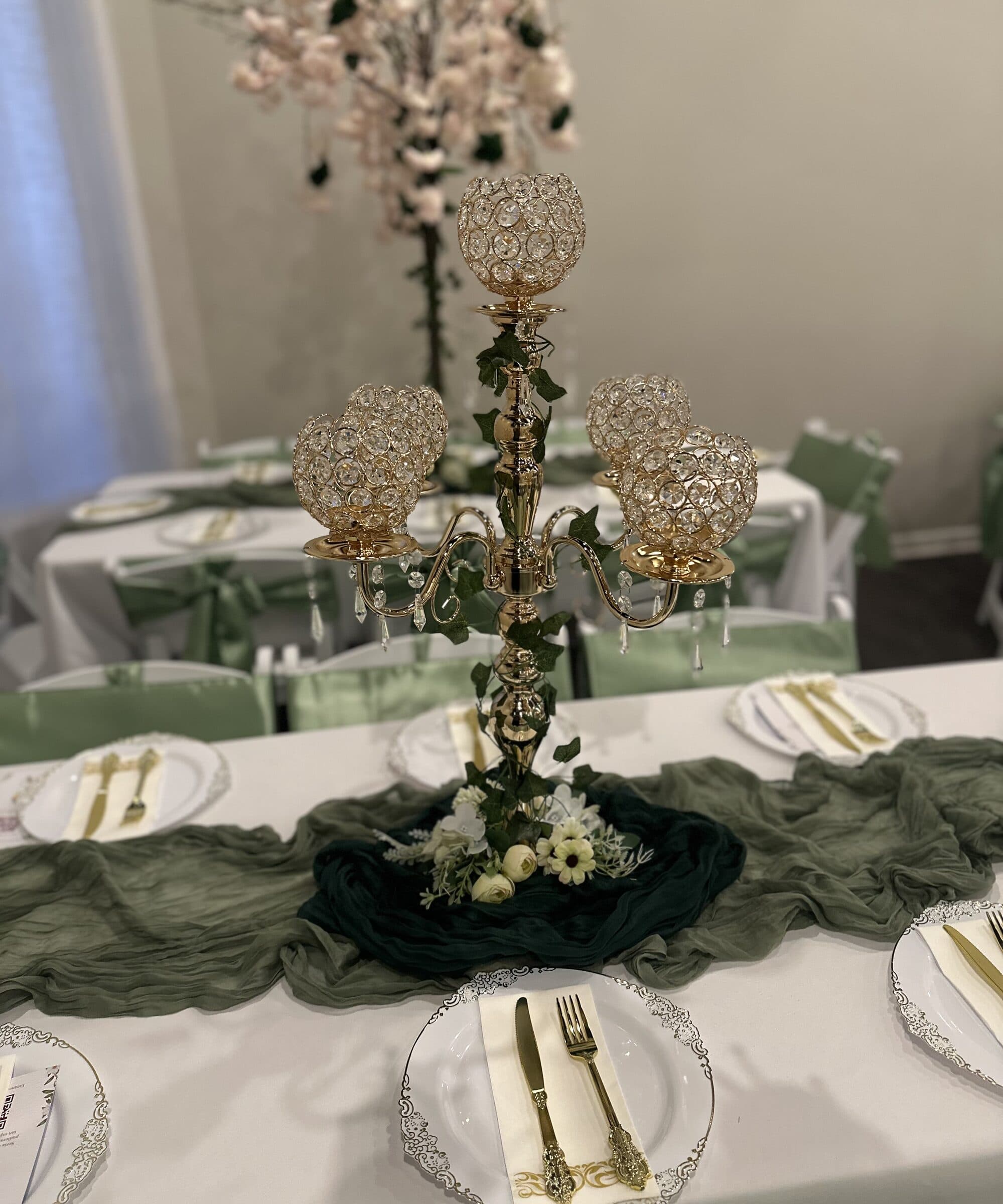 Close-up of the gold crystal-globe candelabra centerpiece with ivy trailing down to white roses on layered olive and forest cheesecloth at The Cove at St. Johns, Fruit Cove FL