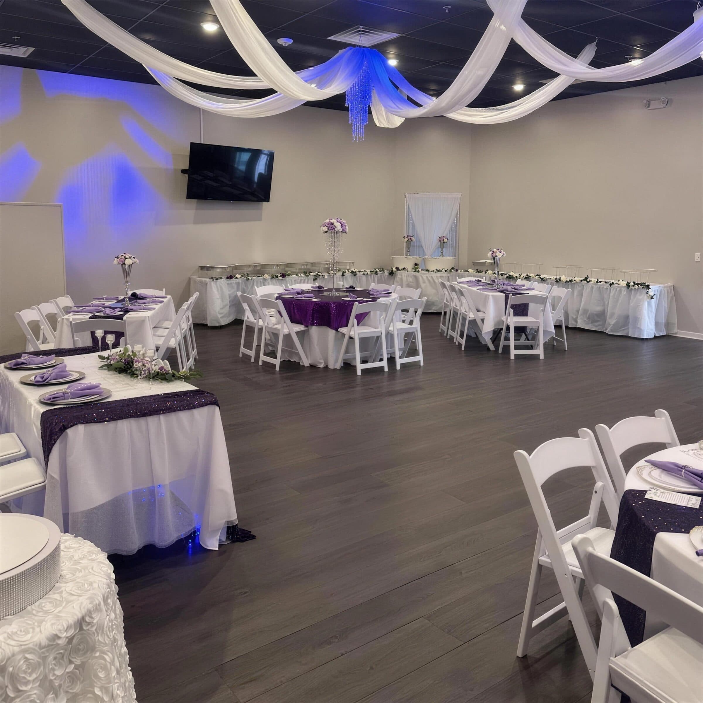 Purple and lavender reception at The Cove at St. Johns, St. Johns County FL - plum sequin overlays, lavender napkins, a buffet line and white ceiling drapes lit blue around a crystal chandelier