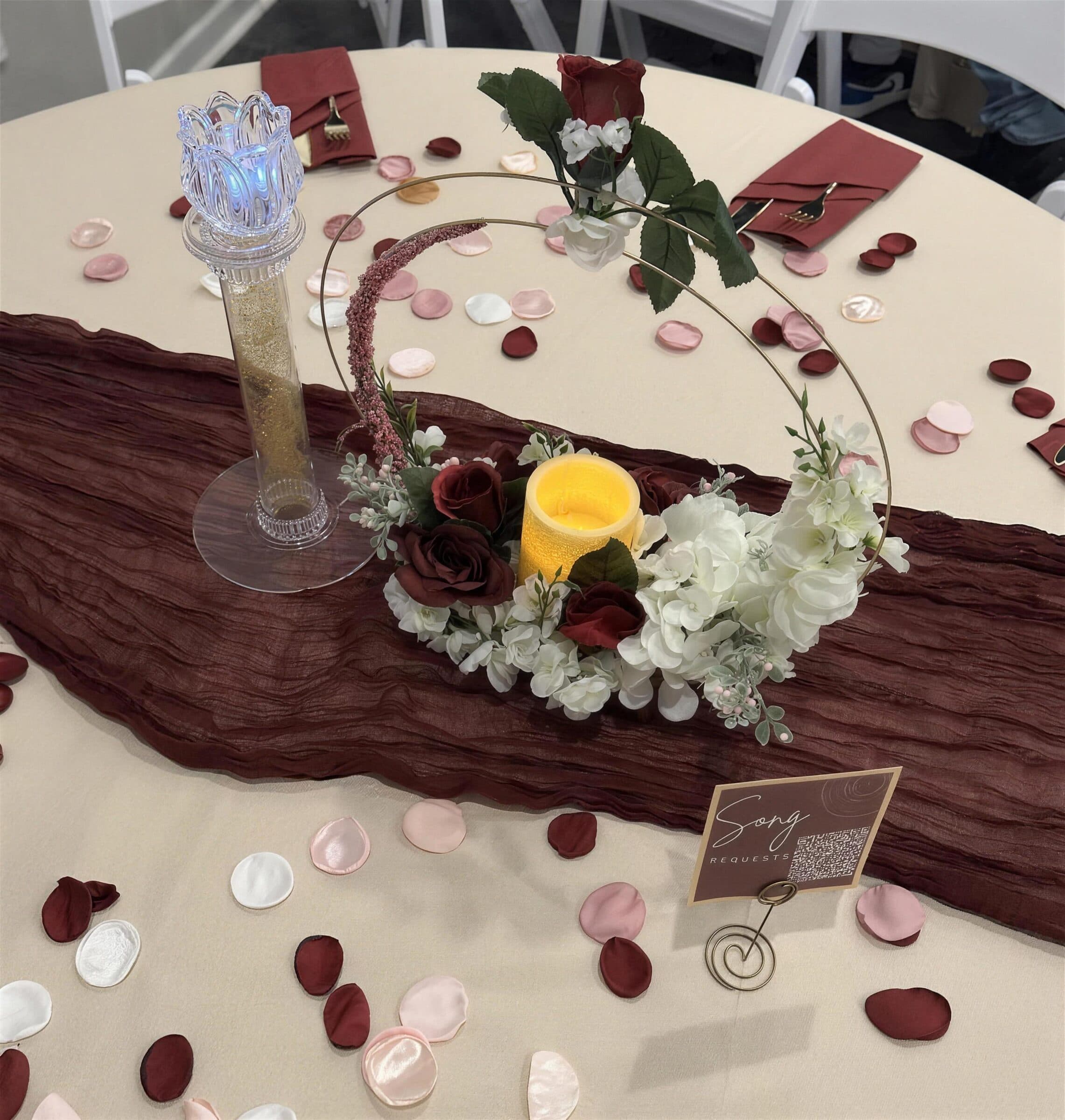 Gold hoop centerpiece of burgundy roses and white hydrangeas around a flameless candle on a burgundy runner strewn with fabric petals at The Cove at St. Johns, near Jacksonville, FL